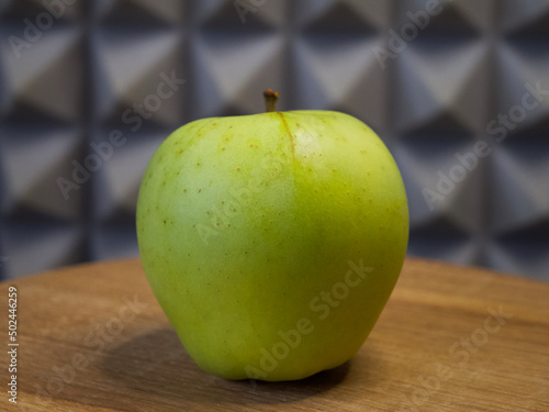 One large apple on a wooden surface, side view. Apple close-up. photo