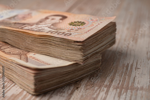 Stack of Thai baht banknotes on wooden background, business saving finance investment concept. photo