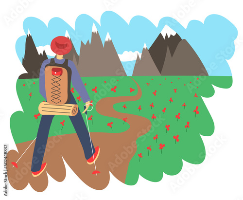 Traveler on a hike walks among the flowers to the mountains