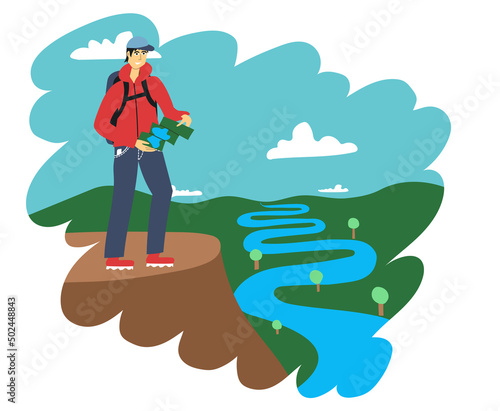Traveler with a map stands on a rock and looks at the river