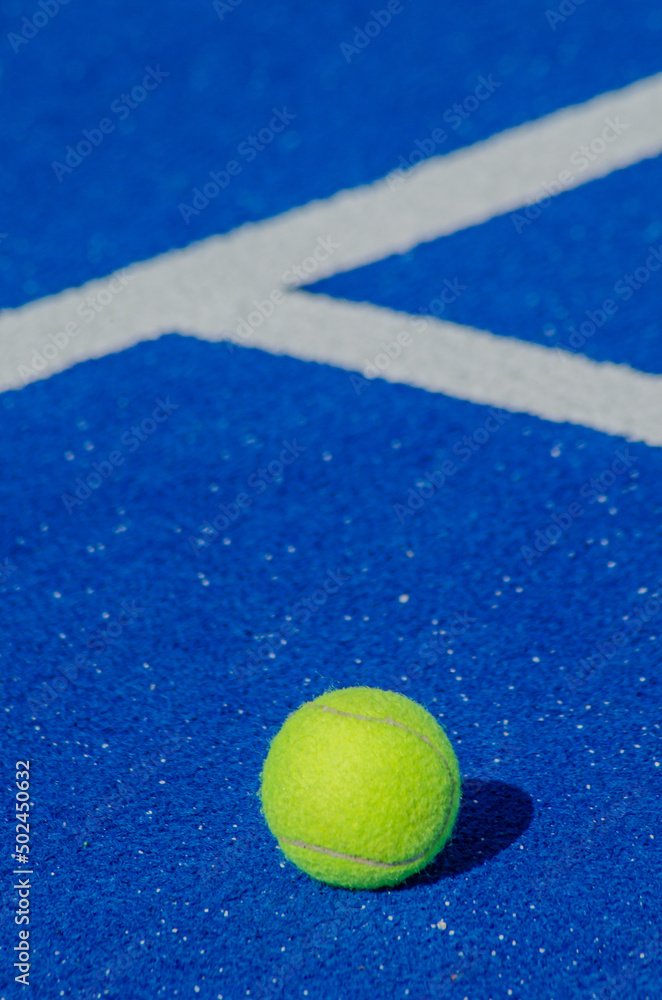 Isolated ball on a blue paddle tennis court, racket sports concept