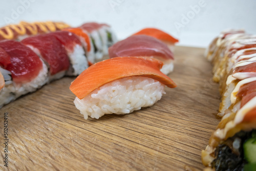 Angled, selective focus view of a variety of sushi rolls on a bamboo cutting board