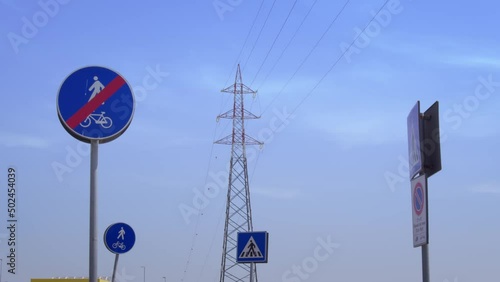 Traliccio dell'elettricità circondato da segnali stradali sotto un cielo azzurro photo
