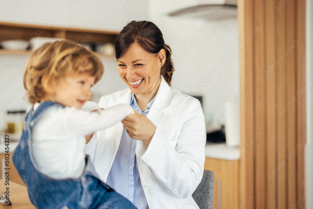 Cute toddler having a doctor's visit at home, holding hands toge Cute toddler having a doctor's visit at home, holding hands toge