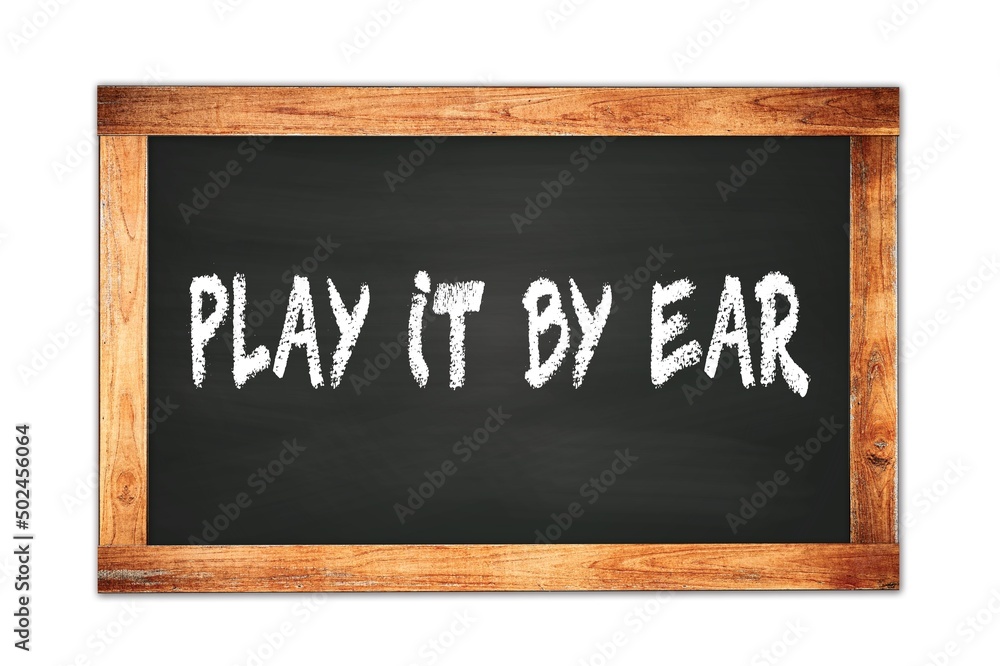 PLAY IT BY EAR text written on wooden frame school blackboard. PLAY IT BY EAR text written on wooden frame school blackboard.