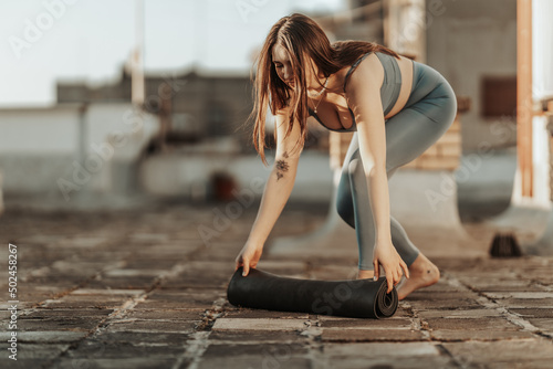 Woman Rolling Up Yoga Mat And Preparing To Outdoors Training