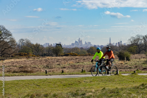 Cyclists in Richmond Park pass a stunning backdrop of the buildings in the centr фототапет