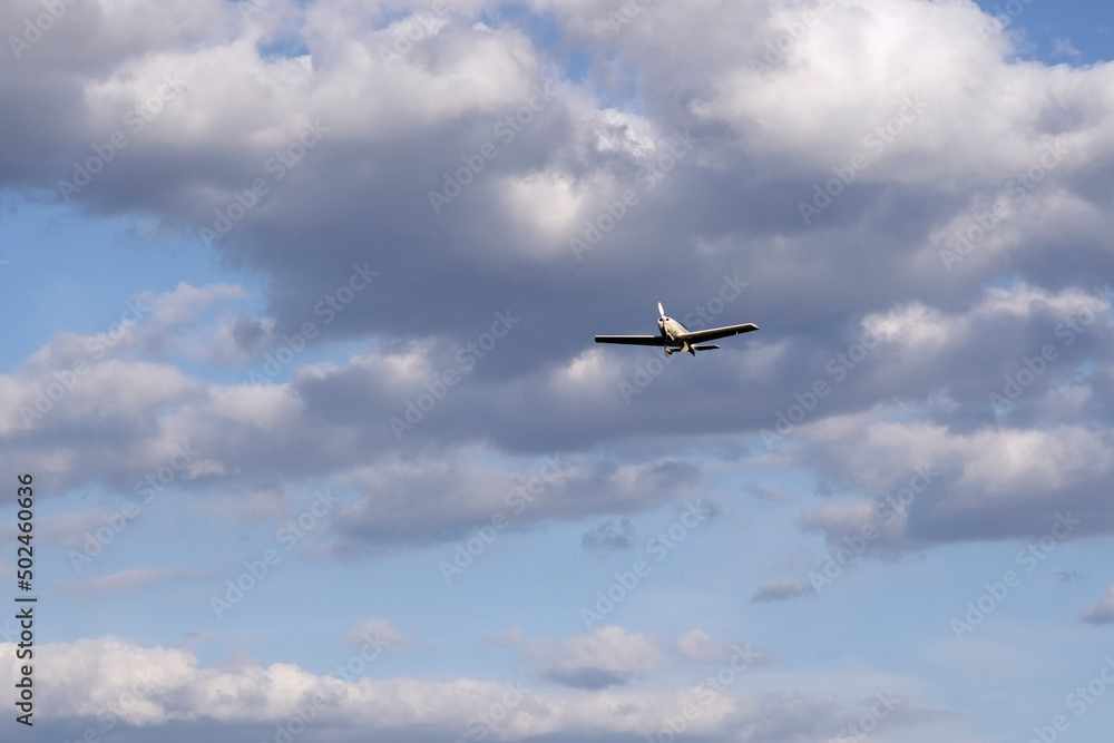 A small plane flies under the clouds. A small plane flies under the clouds.