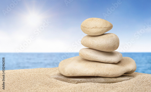Stack of zen stones on sunny sand beach