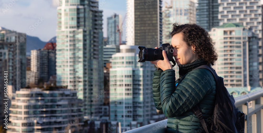 Caucasian Woman with camera taking images of modern cityscape. Travel photographer. Cambie Bridge, False Creek, Downtown Vancouver, British Columbia, Canada. Caucasian Woman with camera taking images of modern cityscape. Travel photographer. Cambie Bridge, False Creek, Downtown Vancouver, British Columbia, Canada.