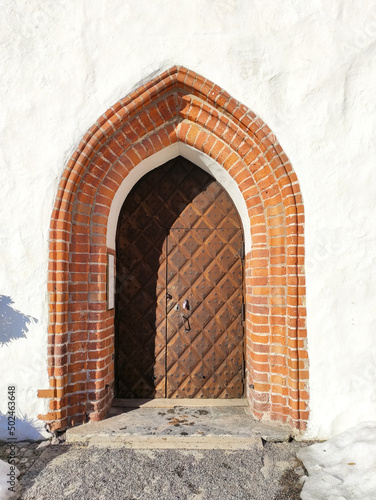 Entrance door on a white wall with red bricks. Antique wooden door. architectural element.