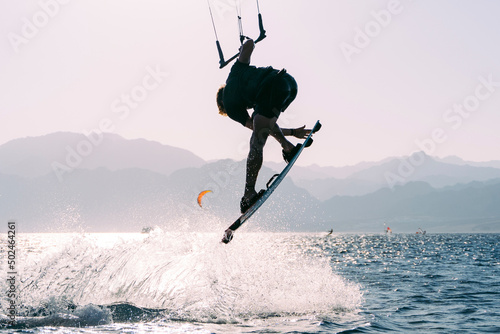 Kiteboarder grabing board after jump with water splashes, Dahab, Egypt photo