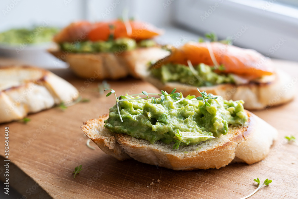 Healthy eating, toast with guacamole and salmon slices, bowl with avocado. Healthy eating, toast with guacamole and salmon slices, bowl with avocado.