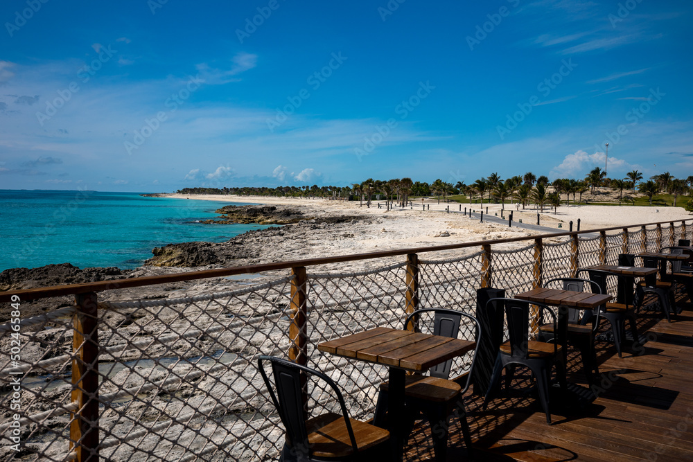 Tables and chairs lined along robe fence bordering tropical beach on the private island coastline