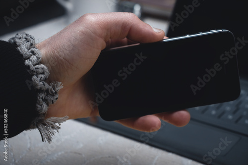 A man s bracelet. The guy holds the phone in his hands in close-up.