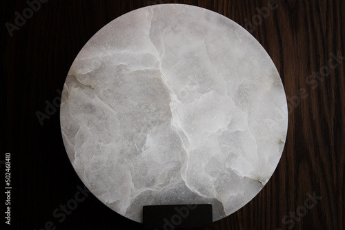 natural textured for a Round piece of white onyx marble fixed on a wooden wall