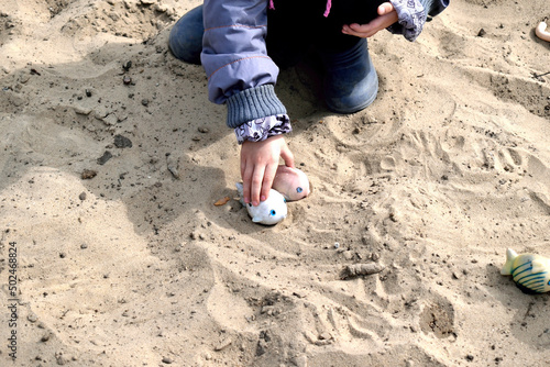 Ukraine. A child plays in the sand between air raids sirens photo