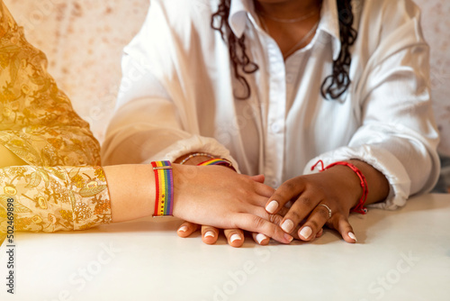 hands of a lesbian couple with rainbow bracelets