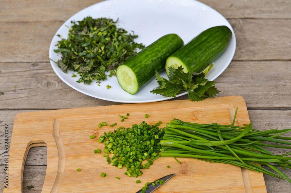 Preparation of spring green vitamin salad from nettle, cucumber and green onion, veganism.