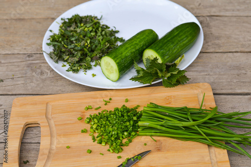 Preparation of spring green vitamin salad from nettle, cucumber and green onion, veganism.