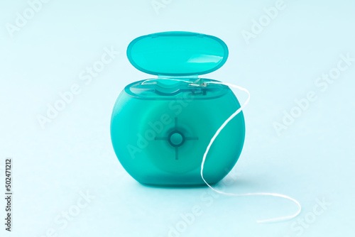 Teal box of dental floss is open on blue background.
