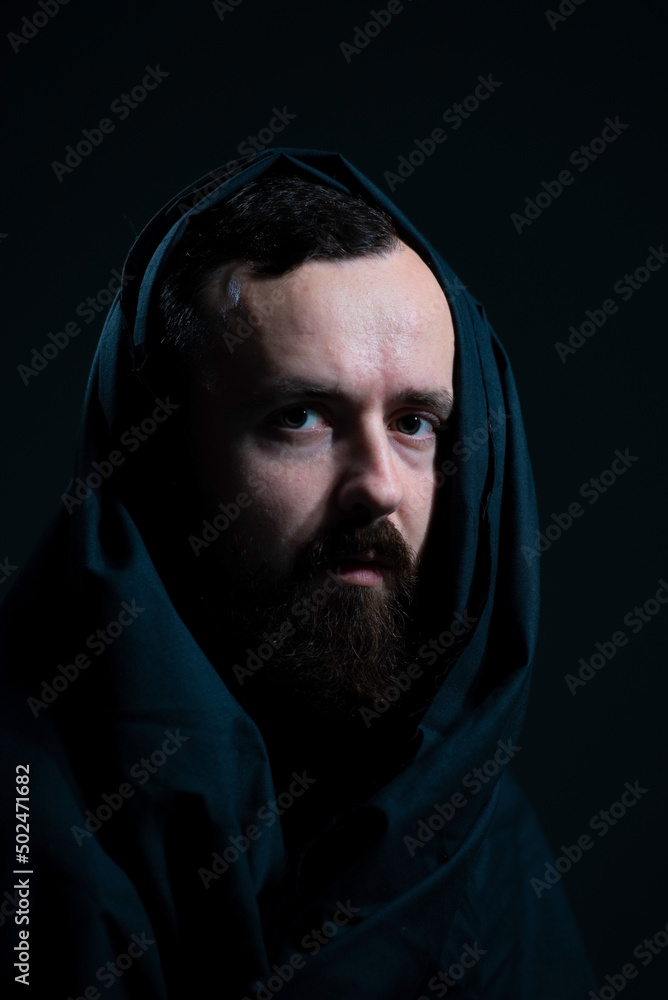 dramatic religious portrait of a bearded guy in a black cape on a dark background dramatic religious portrait of a bearded guy in a black cape on a dark background
