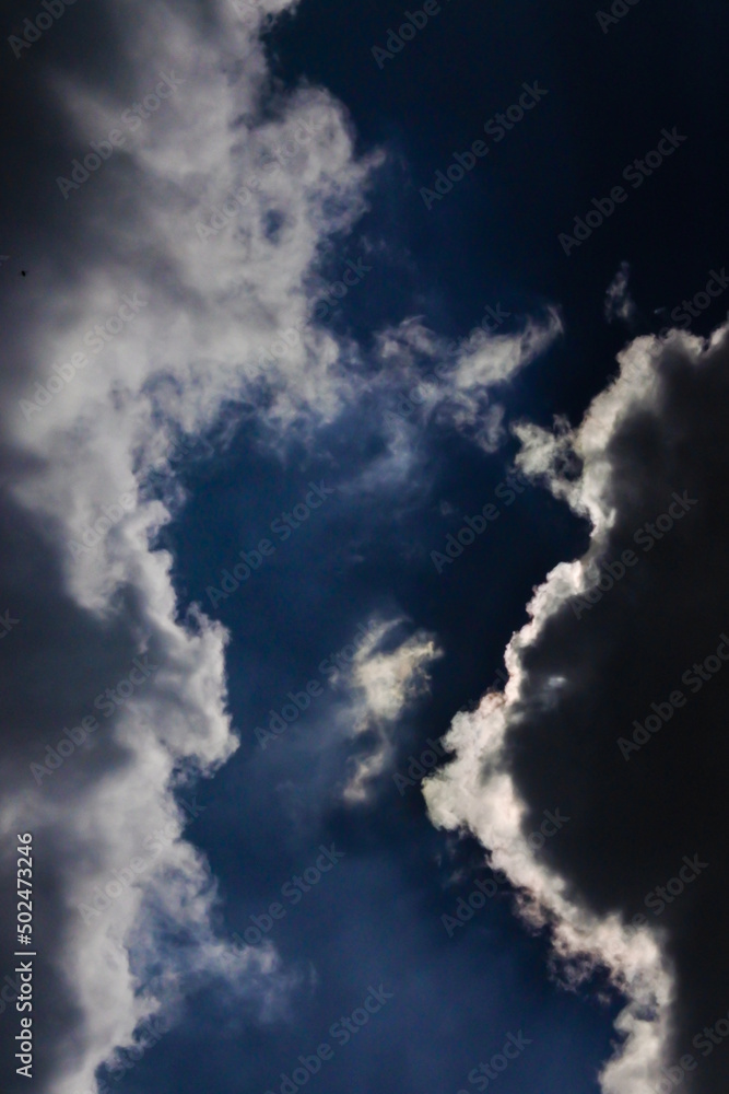 dark blue cloudy sky with dark cumulonimbus clouds covering the sun
