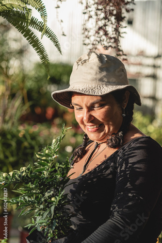 Smiling Latina woman holding a plant in her hands at a nursery plants  photo