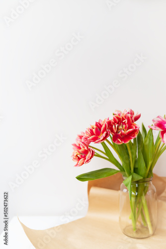 A beautiful spring bouquet of tulips stands in a vase. Surprise concept  birthday. Vertical photo  place for an inscription.