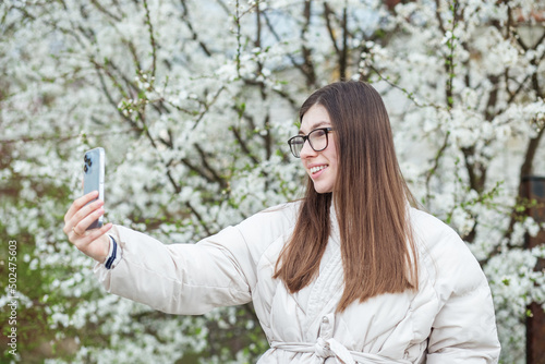 Young adult girl communicates via video chat using mobile device. Spring season.