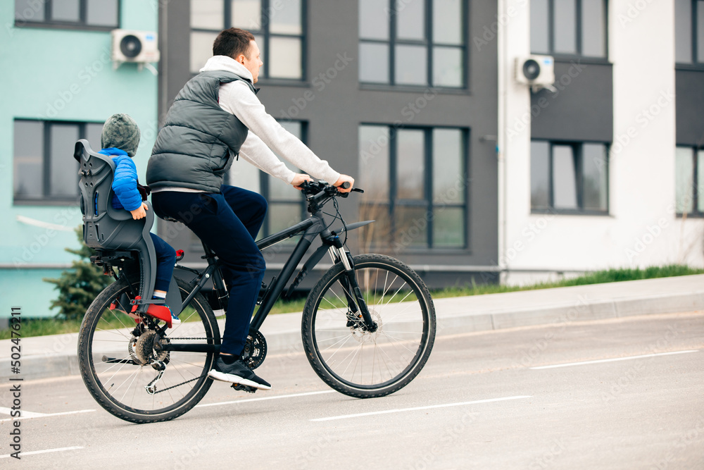 father riding bike with son in bike seat