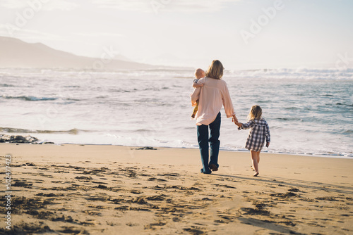 Mother with children playing and having fun together on beach ocean. Happy family outdoors. Mom and kids at summer on nature. Positive human emotions and feelings. Family holiday on sea coast. photo