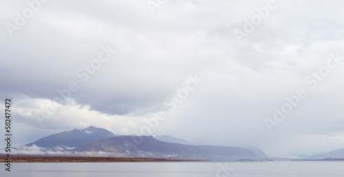 montañas y colinas en la distancia con mar y  nubes nimbostratos blancos y plomos paisaje costanero nublado  panorámico  photo