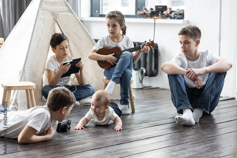 Fototapeta premium Five kids at home in the living room playing games