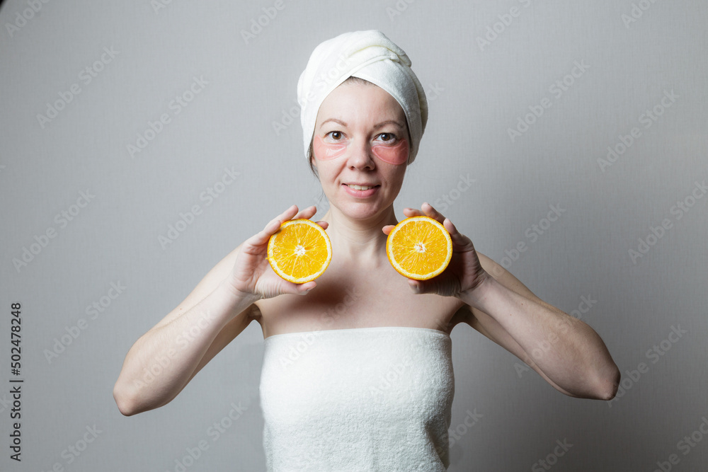 beautiful woman uses eye patches. Woman smiling and holding two halves of an orange beautiful woman uses eye patches. Woman smiling and holding two halves of an orange