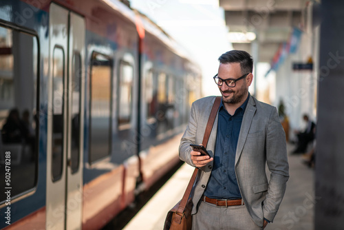 Businessman using mobile phone at train station