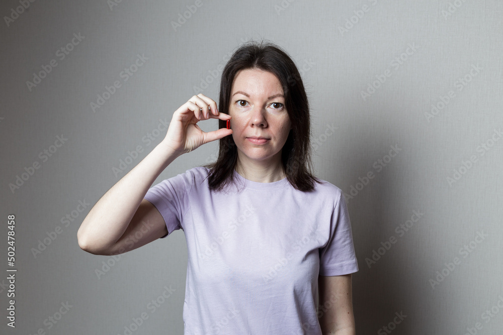 beautiful woman holding a pill in her hands. The girl is going to take a pill. red pill in hand beautiful woman holding a pill in her hands. The girl is going to take a pill. red pill in hand