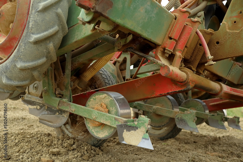 small dusty seeder works on fertile soil, close up shot