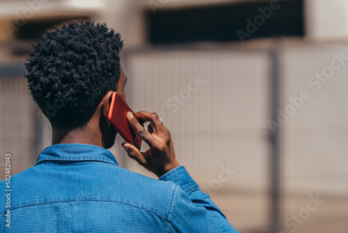 young Afro man talking on his cell phone as seen from behind