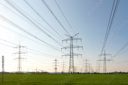 A lot of high-voltage power line, transmission tower overhead line masts, high voltage pylons also known as power pylons on the fields with grain. 