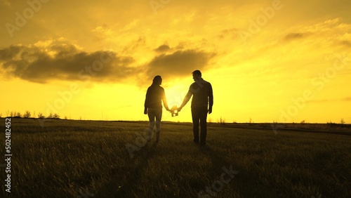 Family's hands are holding paper house at sunset, sun is shining through window. Symbol of house, happiness. Concept of building house for family. Dream to buy house. Family silhouette, family home