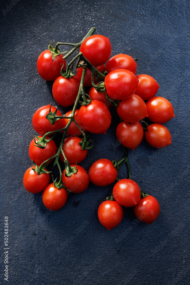 Red cherry tomatoes bunch on a black background, top view Red cherry tomatoes bunch on a black background, top view