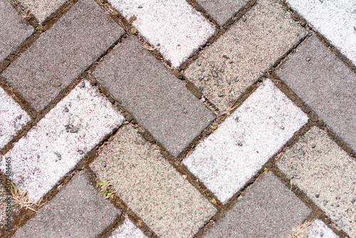 Closeup of sidewalk paved with rectangular white and gray tiles in top view