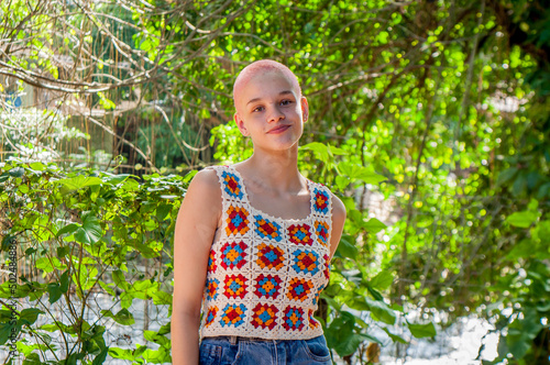 Portrait of a girl with very short hair, dyed pink. Portrait of girl wearing crochet outfit. Portrait of almost bald girl.