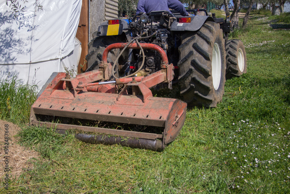 Obraz premium Farmer driving a tractor in the countryside while cutting the grass with a forage harvester