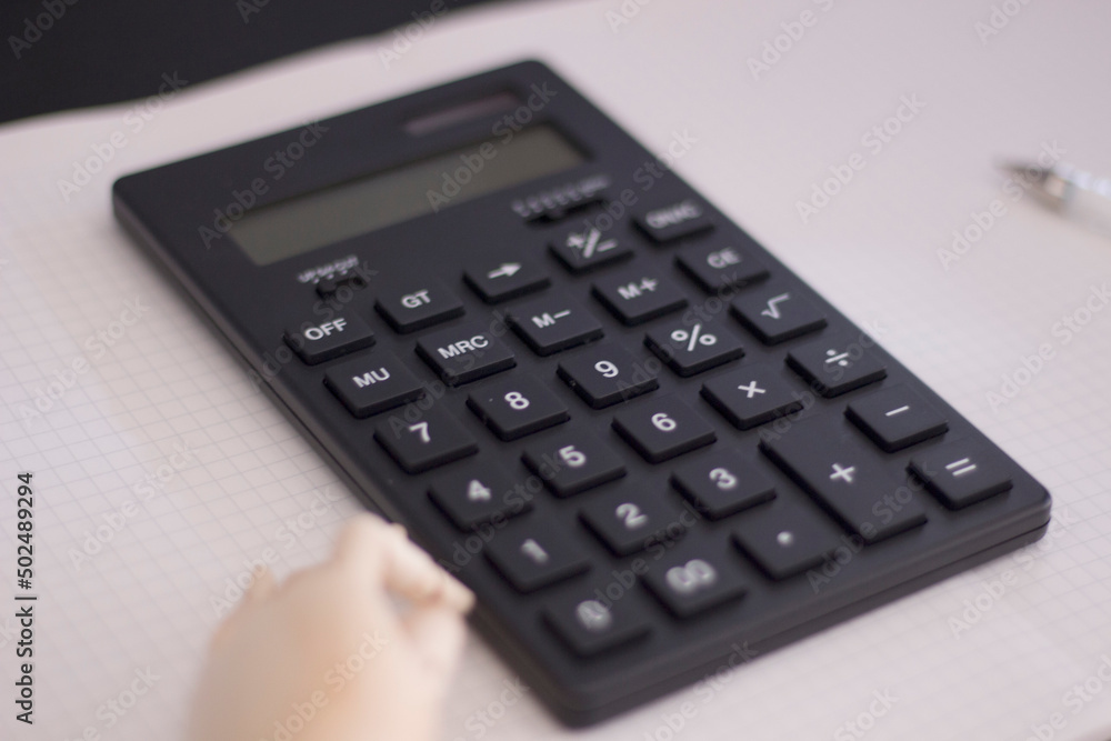 電卓 計算 計算機 / a calculator and a hand on white note 電卓 計算 計算機 / a calculator and a hand on white note