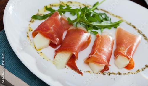 Thin slices of jamon served with melon and arugula – national Spanish snack