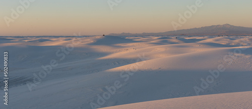 Couples sitting on top of the dunes in White Sands National Park watching the sun set