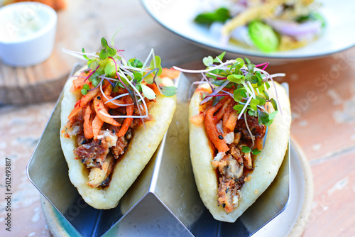A pair of healthy, tasty gourmet Korean tacos with a bao bun at a hip urban restaurant photo