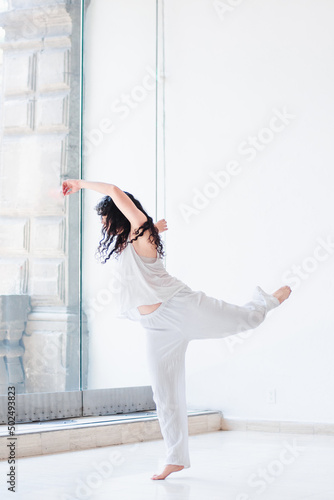 Fototapeta Naklejka Na Ścianę i Meble -  Young woman in white clothes dancing in a studio